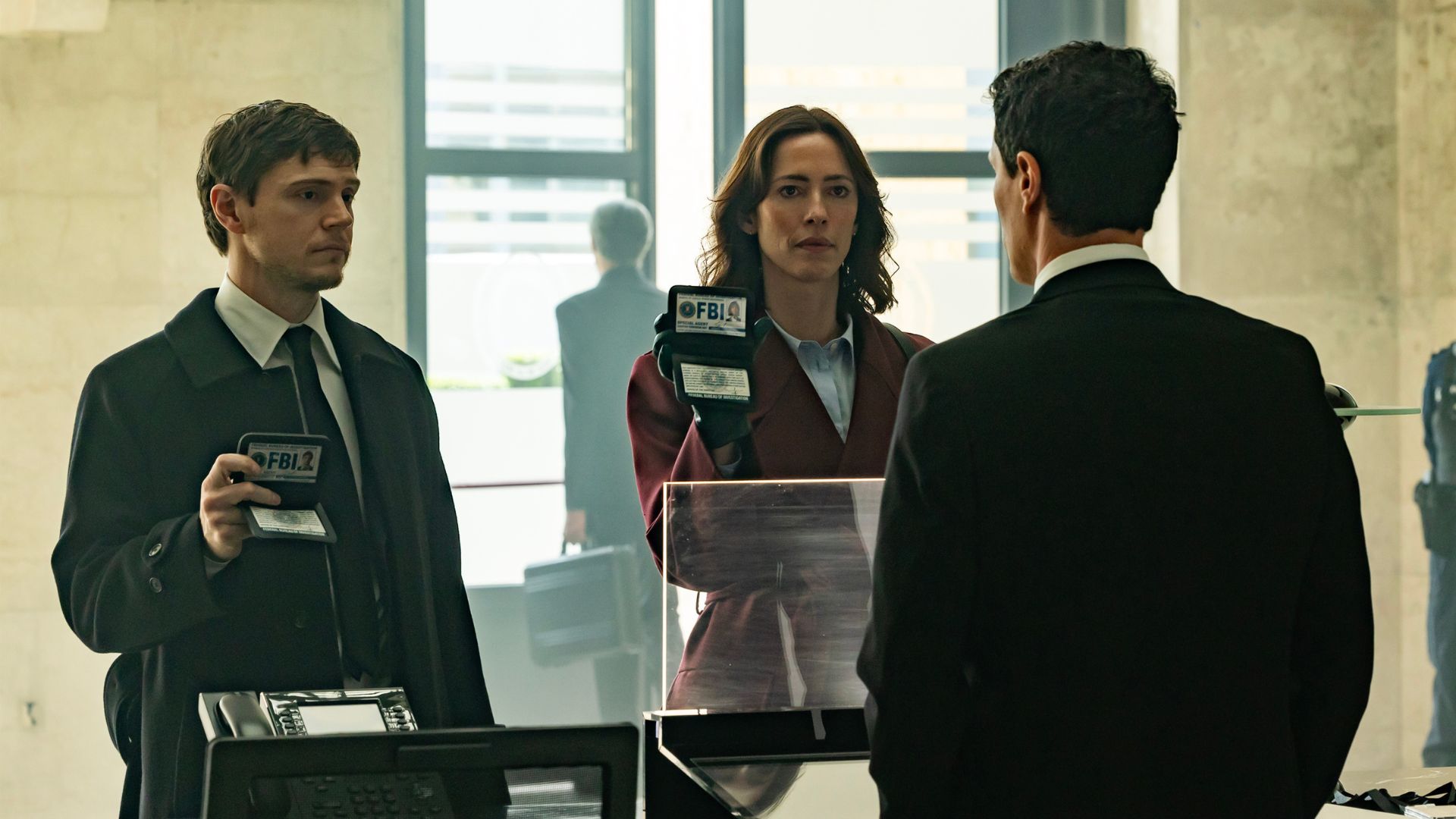 Evan Peters and Rebecca Hall hold up FBI IDs to a man's face