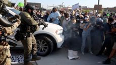 Protesters, including candidates for the 9th Congressional District, are enveloped in a cloud of gas released by federal agents while they attempt to block a vehicle at the Broadview Immigration and Customs Enforcement facility on Sept. 19, 2025, in Broadview, Illinois. Bushra Amiwala, beige sweater, center right, a Skokie school board member, stands next to Kat Abughazaleh, a progressive content creator. Evanston Mayor Daniel Biss, far left with gray hair, wears a black face mask. (Stacey Wescott/Chicago Tribune/Tribune News Service via Getty Images)