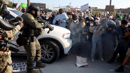 Protesters, including candidates for the 9th Congressional District, are enveloped in a cloud of gas released by federal agents while they attempt to block a vehicle at the Broadview Immigration and Customs Enforcement facility on Sept. 19, 2025, in Broadview, Illinois. Bushra Amiwala, beige sweater, center right, a Skokie school board member, stands next to Kat Abughazaleh, a progressive content creator. Evanston Mayor Daniel Biss, far left with gray hair, wears a black face mask. (Stacey Wescott/Chicago Tribune/Tribune News Service via Getty Images)