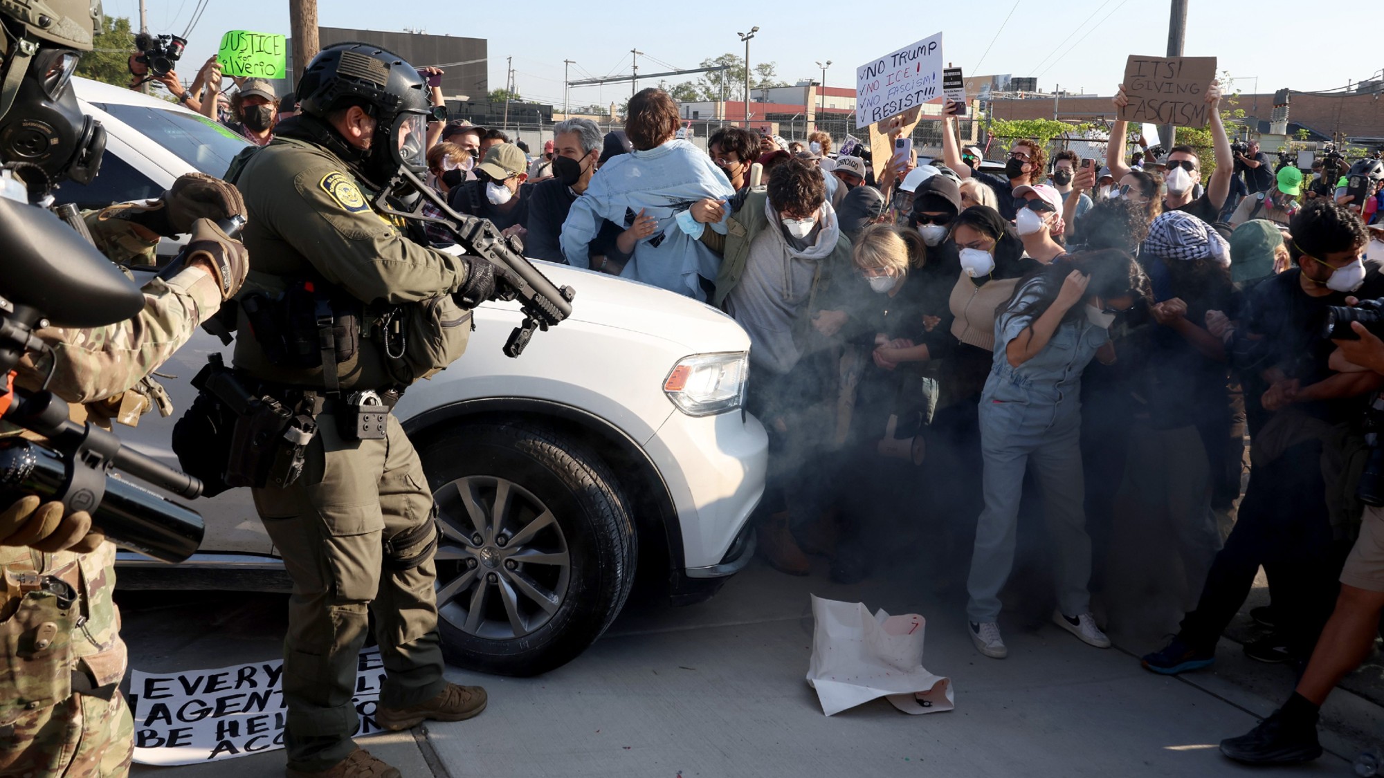 Protesters, including candidates for the 9th Congressional District, are enveloped in a cloud of gas released by federal agents while they attempt to block a vehicle at the Broadview Immigration and Customs Enforcement facility on Sept. 19, 2025, in Broadview, Illinois. Bushra Amiwala, beige sweater, center right, a Skokie school board member, stands next to Kat Abughazaleh, a progressive content creator. Evanston Mayor Daniel Biss, far left with gray hair, wears a black face mask. (Stacey Wescott/Chicago Tribune/Tribune News Service via Getty Images)