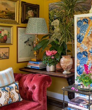 Corner of a yellow living room with a gallery wall and plants