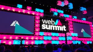 A screen displaying the Web Summit logo in a darkened room