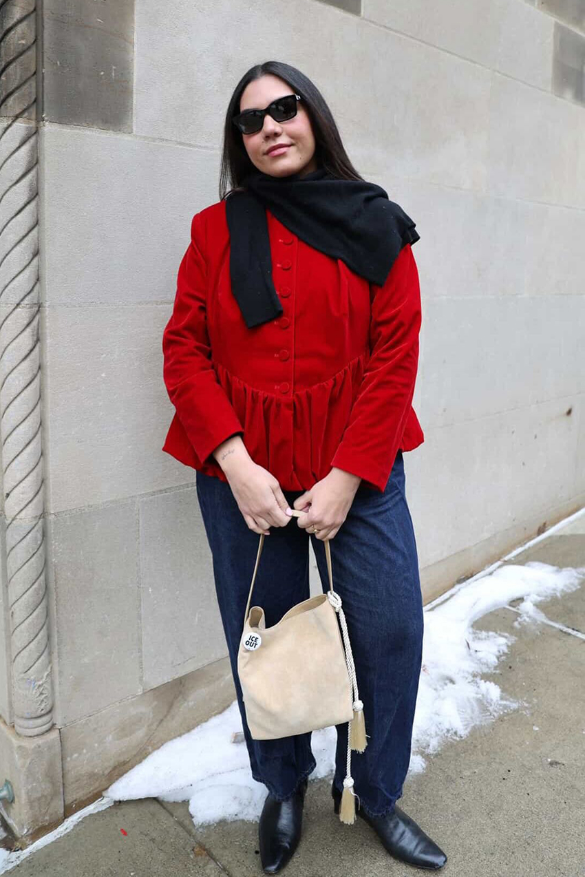 a woman wearing a red peplum top and jeans, and a beige bag