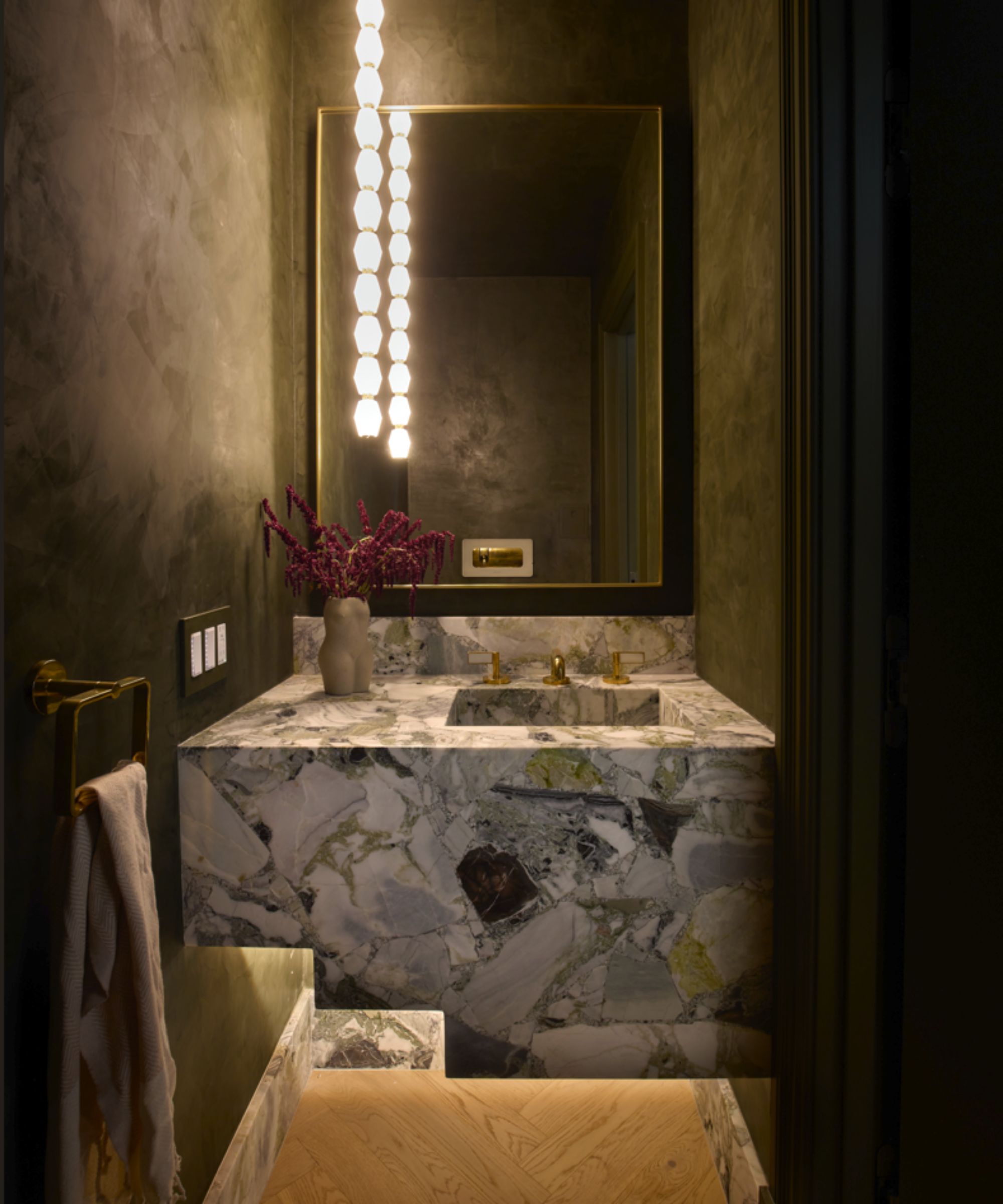 Dark powder room with block marble sink, rectangular mirror, textured dark green painted walls, wooden flooring