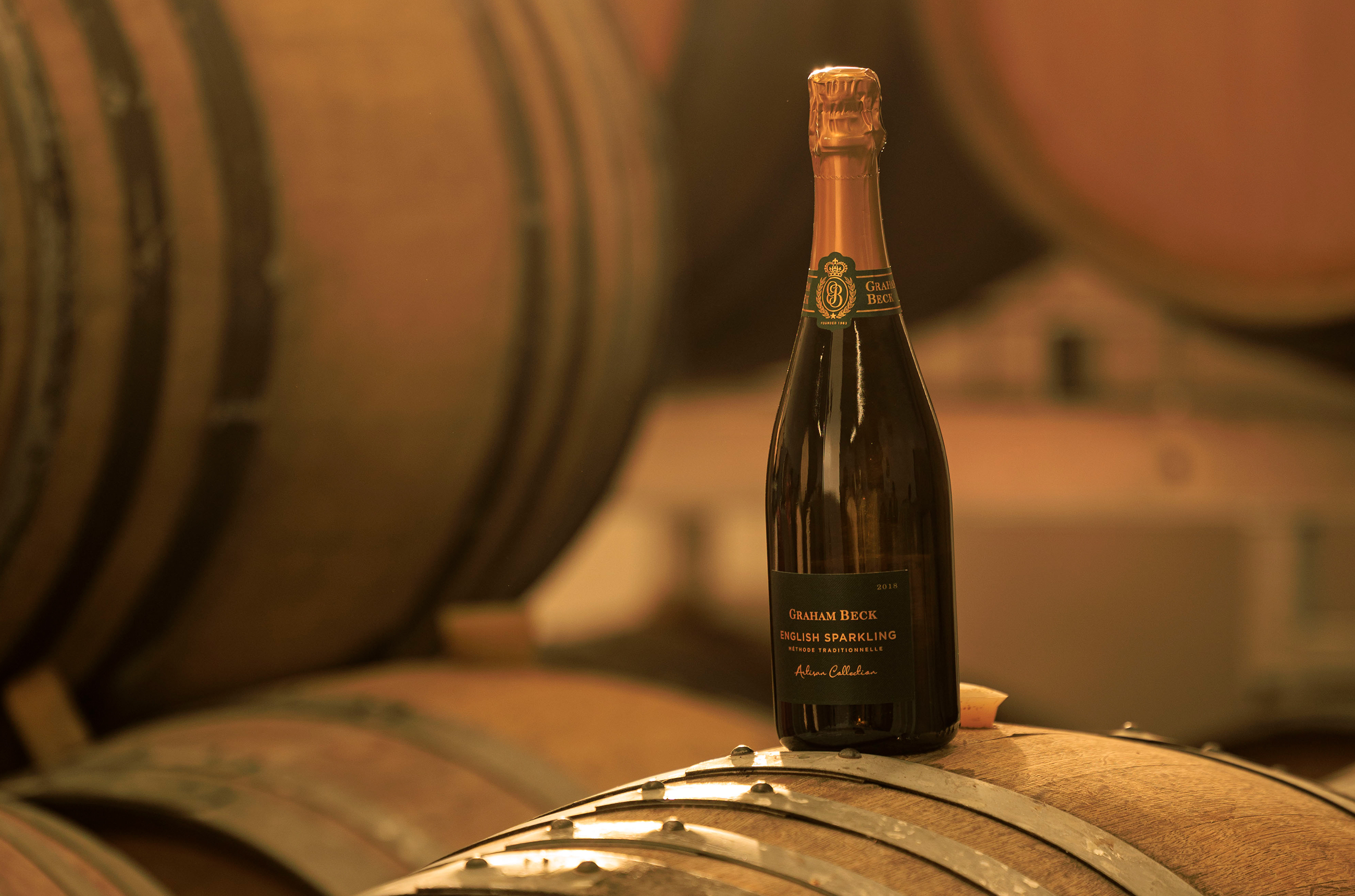 A bottle of Graham Beck English sparkling wine on top of a barrel