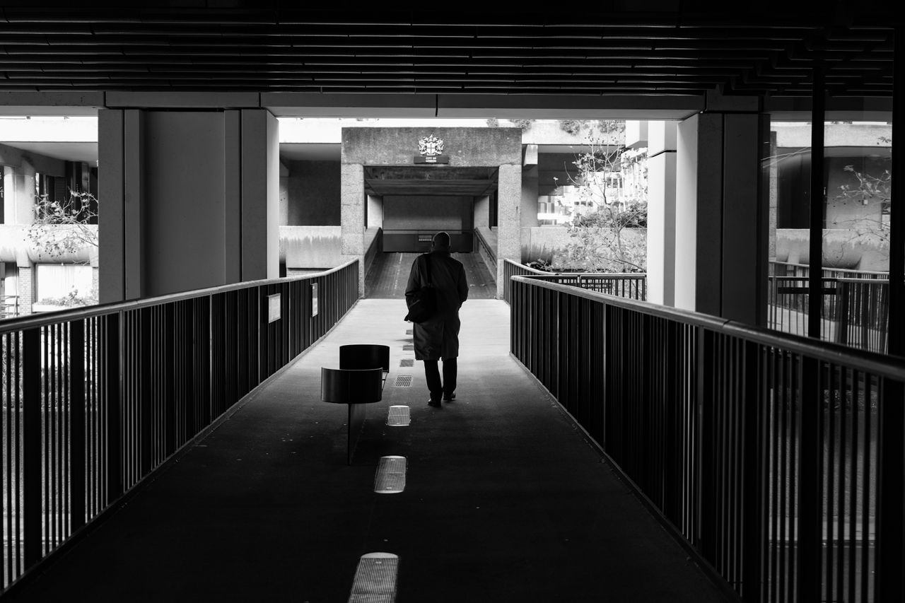 Man walking under a bridge in black-and-white
