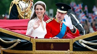 Catherine, Duchess of Cambridge and Prince William, Duke of Cambridge (wearing his red tunic uniform of the Irish Guards, of which he is Colonel) travel down The Mall, on route to Buckingham Palace, in the 1902 State Landau horse drawn carriage following their wedding ceremony at Westminster Abbey on April 29, 2011 in London, England.