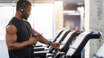 A man in the gym figuring out how to use a treadmill