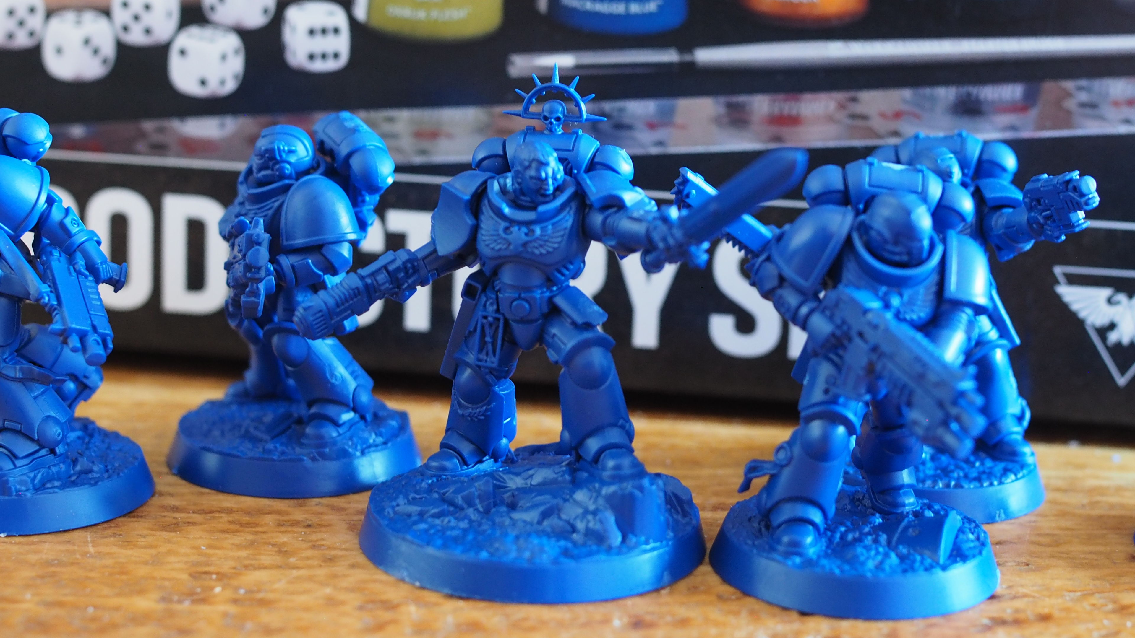 A selection of Space Marine miniatures on a wooden table, in front of the Warhammer 40,000 Introductory Set box