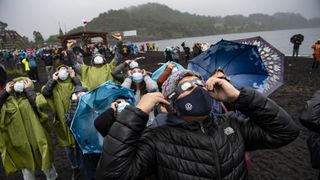 People watch a total solar eclipse on the shores of Lake Villarrica in Pucón, southern Chile, on December 14, 2020.