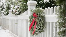 A christmas wreath on a snowy, white wooden railing