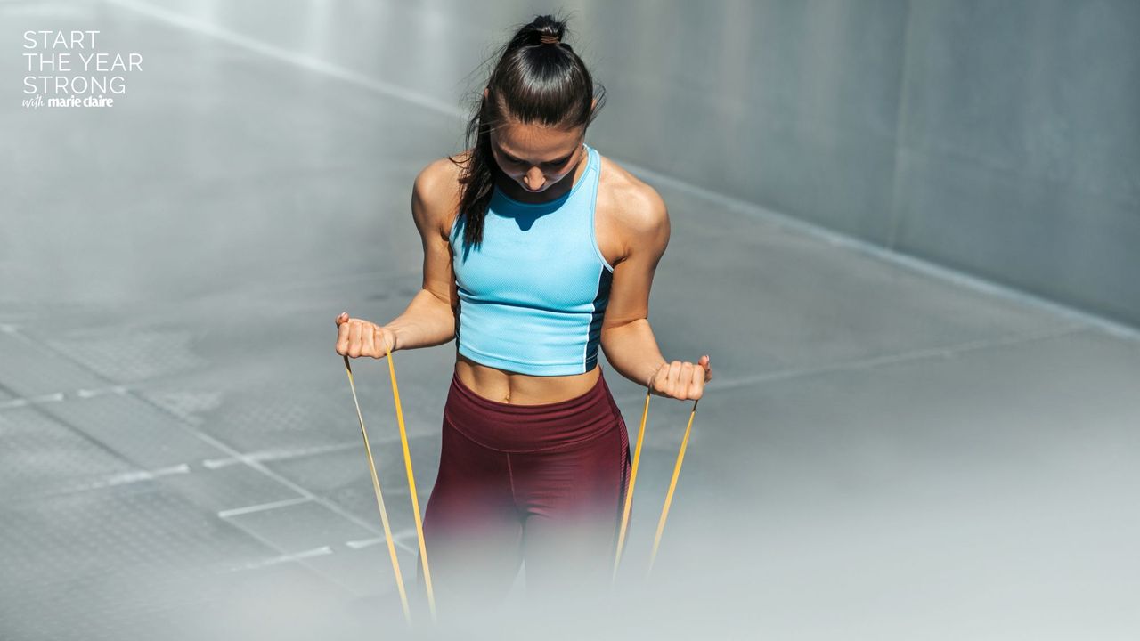 A woman doing some of the best resistance band exercises in blue and purple gym kit