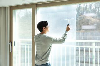 A man applying bubble wrap to his windows
