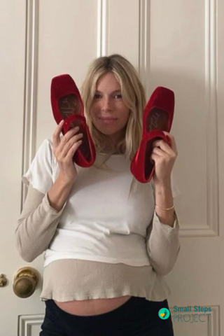 Sienna Miller holding her shoes ahead of the auction.