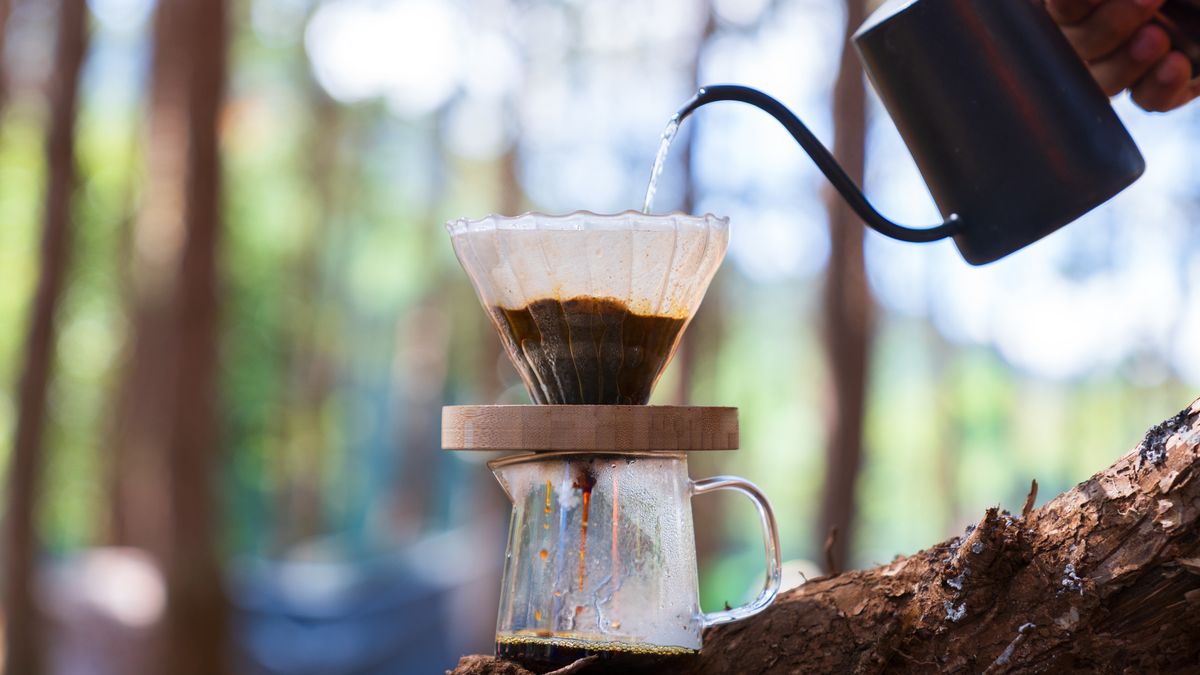 A camper pouring coffee in the woods