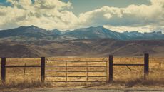 Beautiful view of a ranch and ranch gate with mountains in the distance.