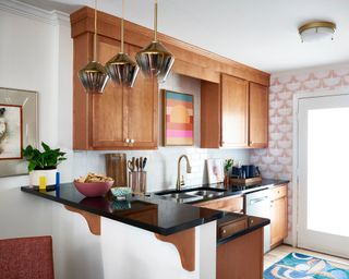 kitchen with wooden cabinets and pink patterned wallpaper