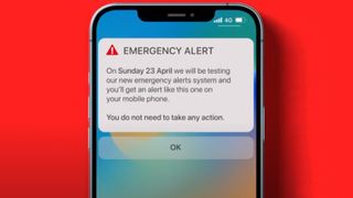 A smartphone on a red background showing the UK emergency alert test