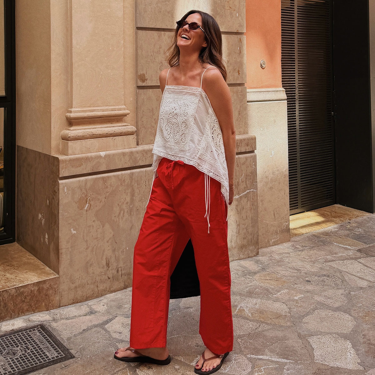 Woman in a white eyelet top and red poplin pants