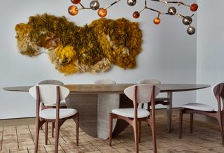 a living room with a textured wall art and curved dining table