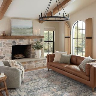 A living room with a blue patterned rug, a leather sofa and a farmhouse style