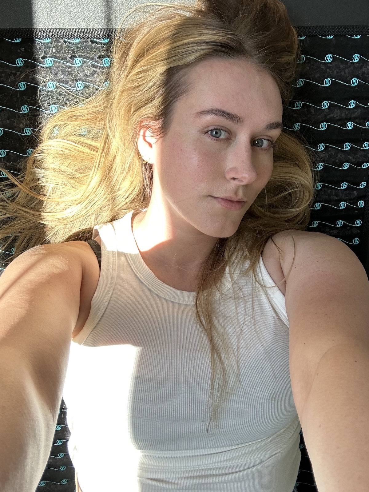 Beauty editor Kaitlyn McLintock lying on the Higher Dose PEMF mat