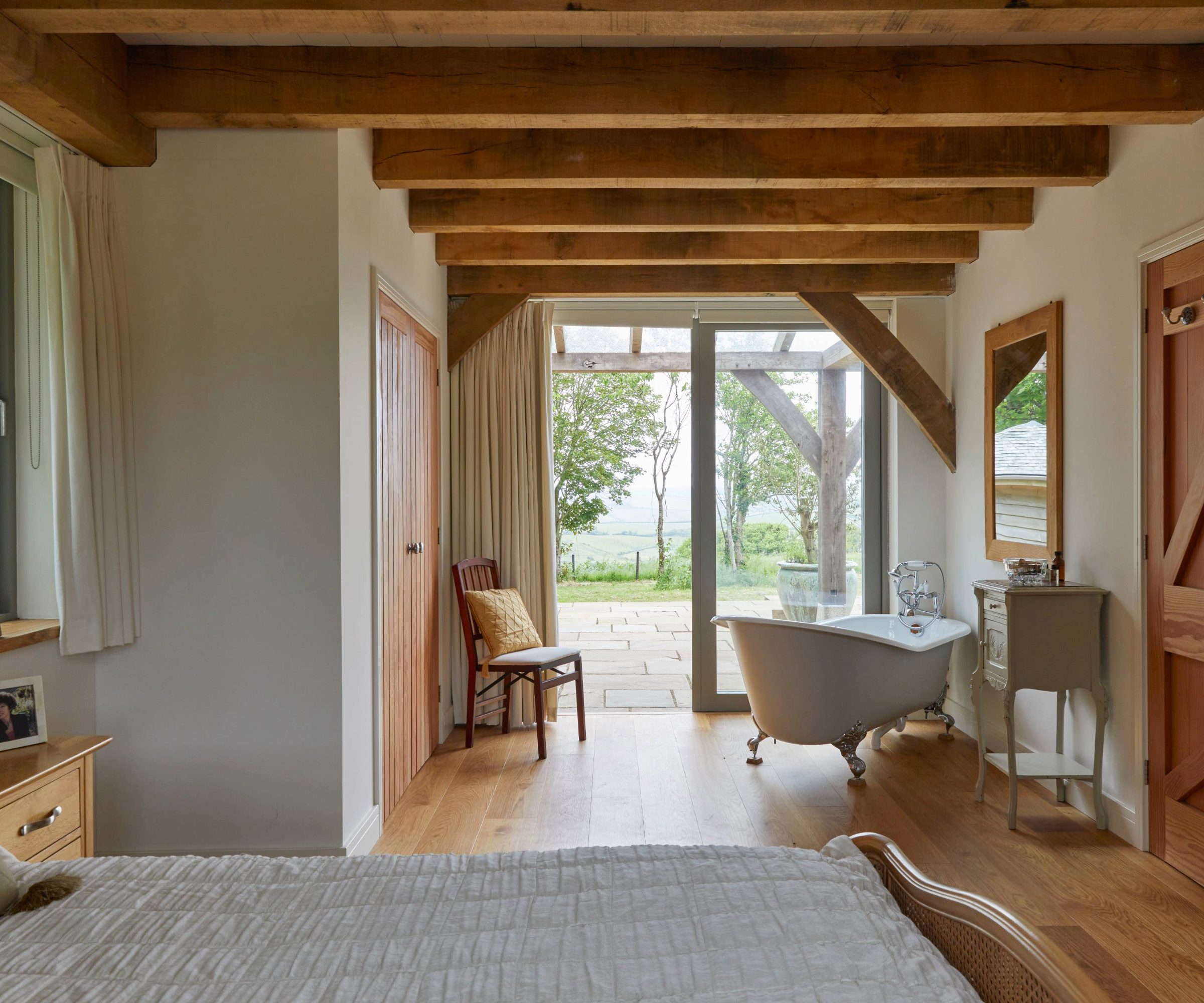 Bedroom with bath overlooking doors onto veranda with countryside views
