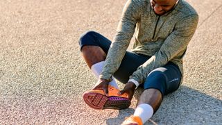 Man wearing running clothing holding foot in pain