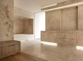 One bathroom is crafted in travertine with wood accents