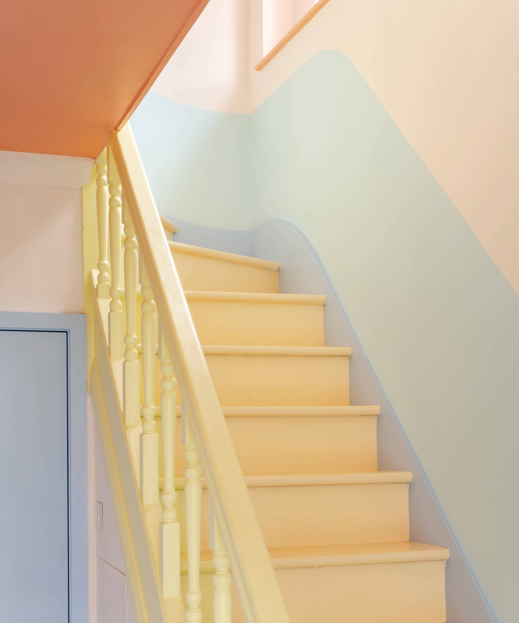Pastel yellow staircase with multicoloured wall