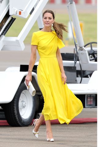 Kate Middleton wears a yellow dress and white and gold heels during the official arrival at Norman Manley International Airport on March 22, 2022 in Kingston, Jamaica.