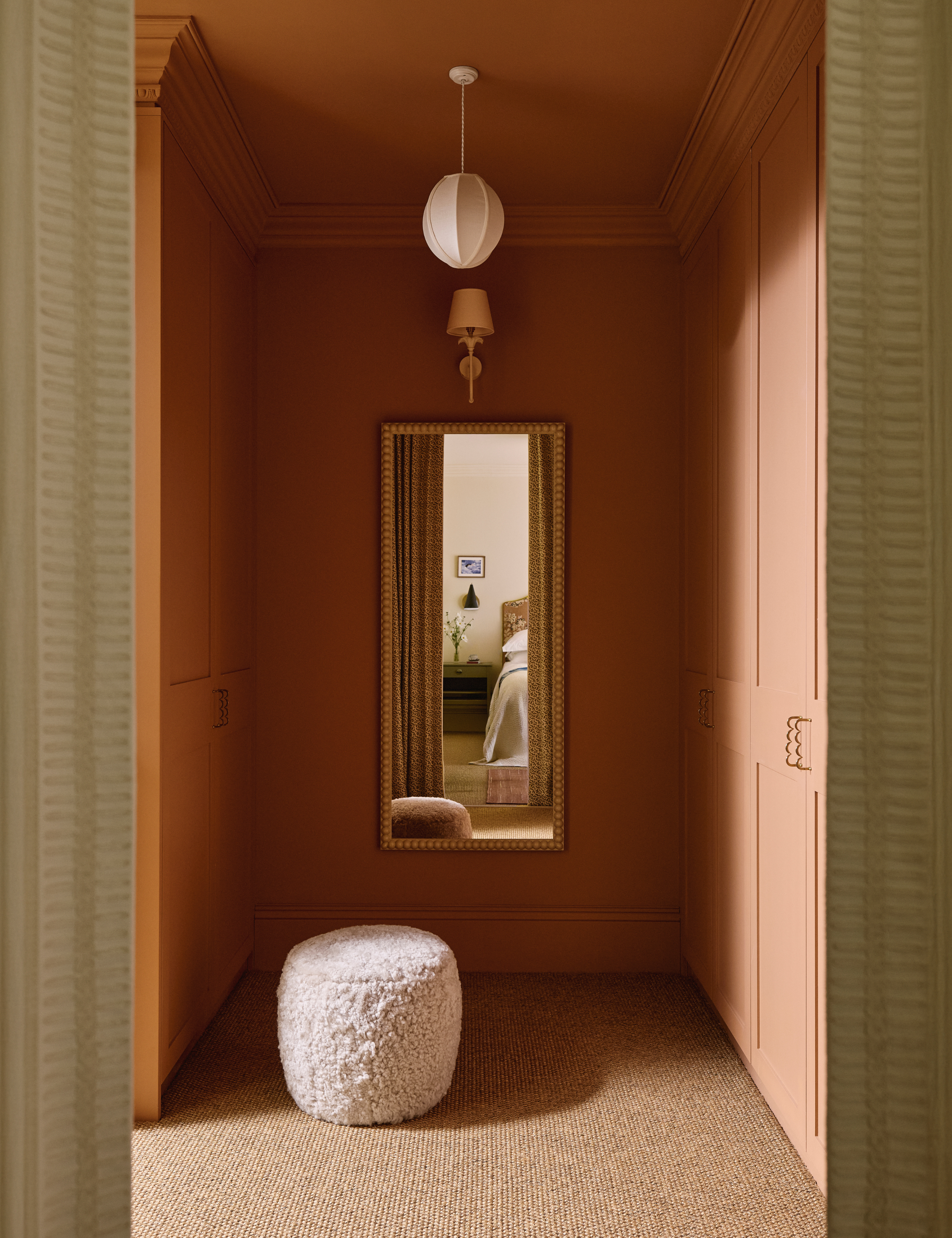 Vertical wall mirror mounted to a peach colored bedroom wall
