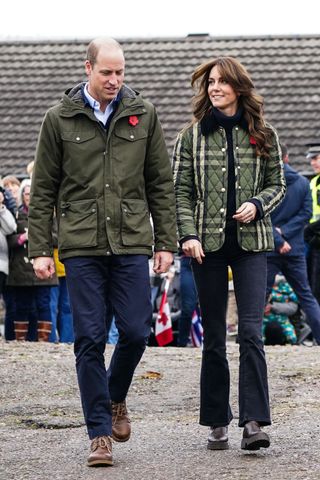 Prince William and Kate Middleton wearing rain jackets and dark jeans on an overcast day