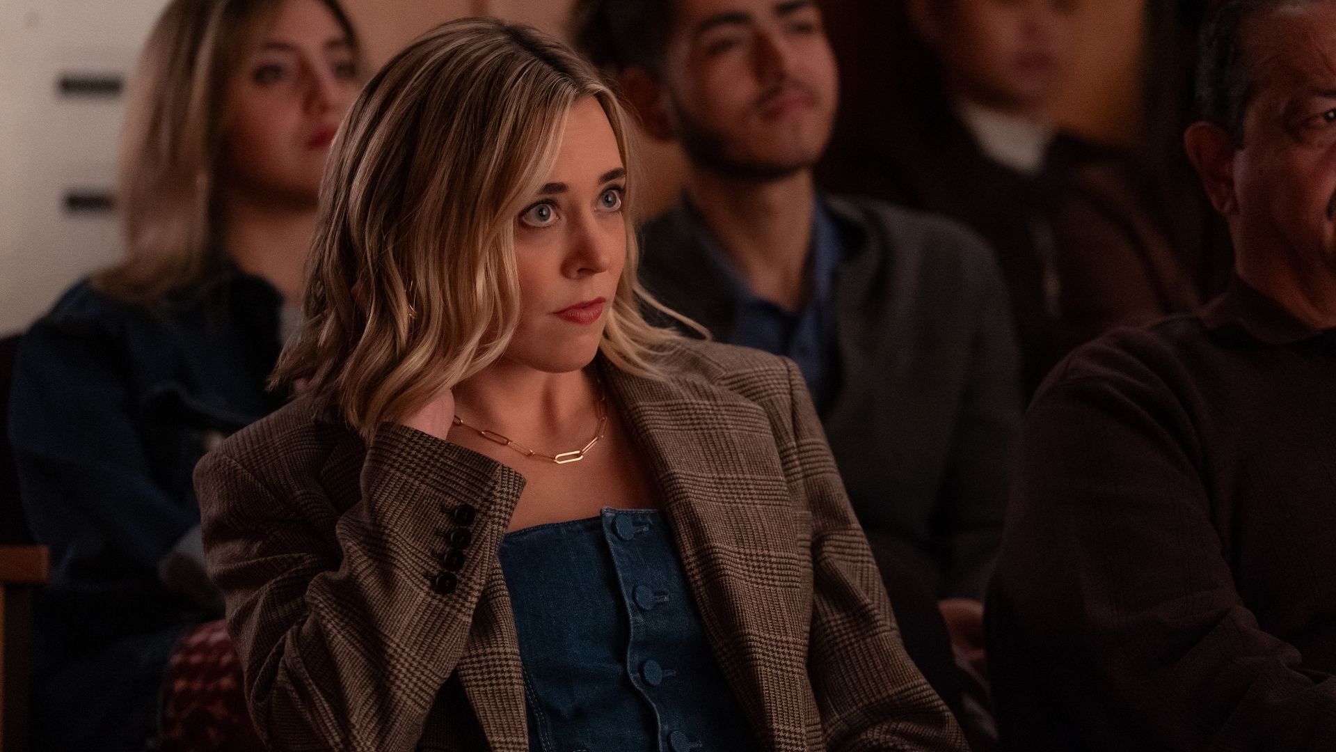 Ginny looks worried sitting in a crowd in The Four Seasons