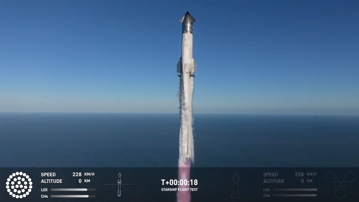 a huge white rocket launches into a blue sky with the ocean in the background