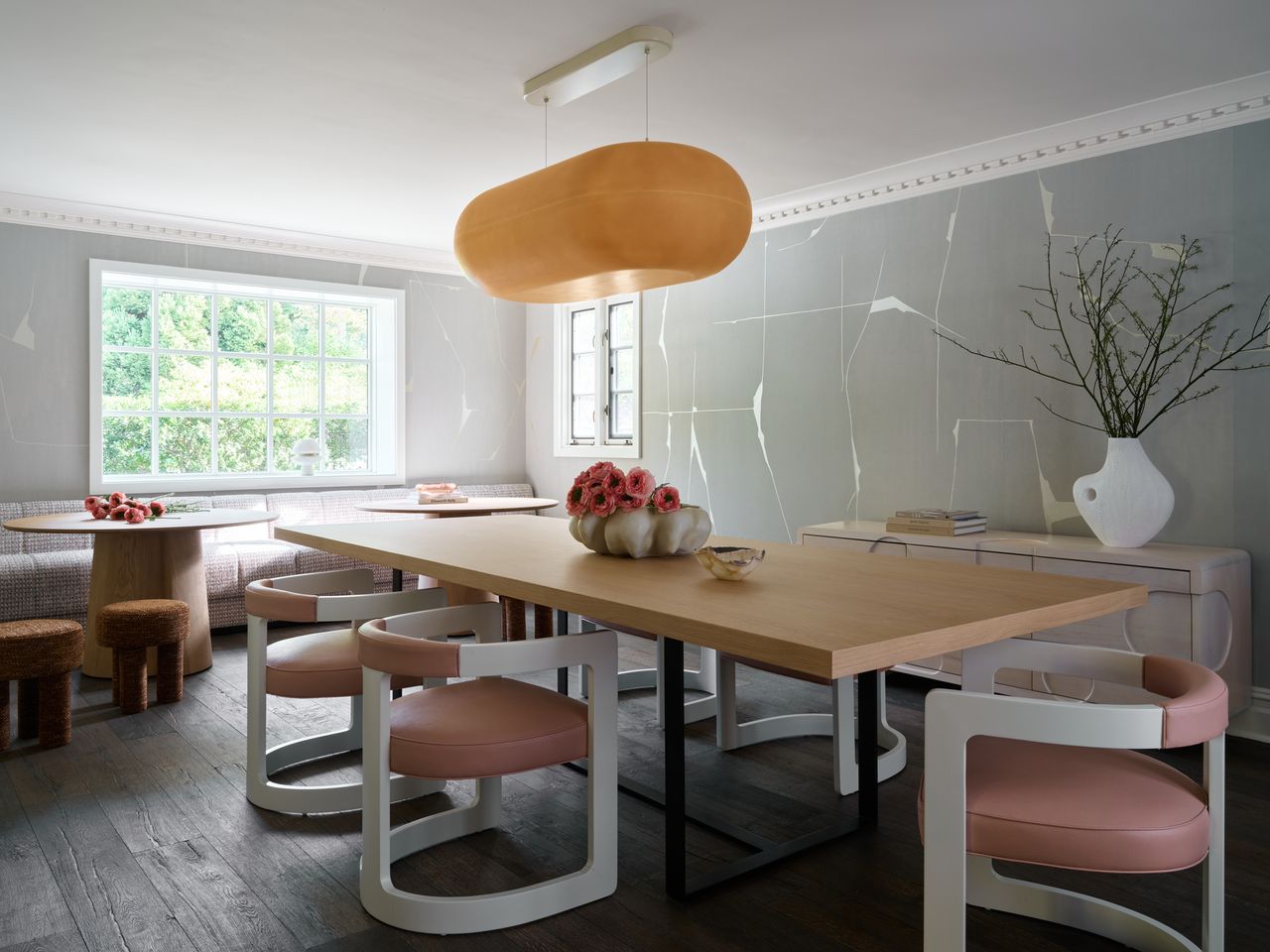 a large dining room with wooden table, chairs and a hanging light fixture