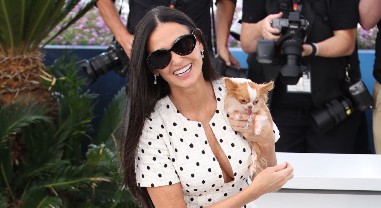 Demi Moore wearing a polka dot dress and holding her dog, Pilaf, in Cannes