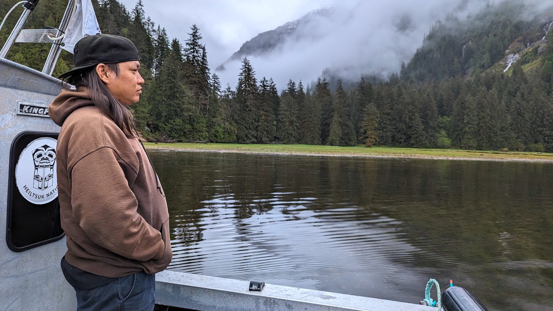 A man stands on a boat and looks out onto the water