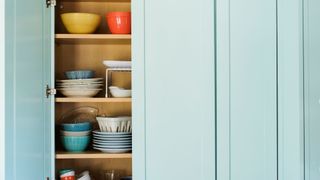 inside a kitchen cabinet with various dishes and light blue doors