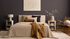 Bedroom with French Press Coffee walls, a large bed with neutral bedding, two white nightstands, a rattan lounge chair and a cream rug.