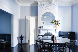 A dining room painted blue, flowing into a living room in the same tone