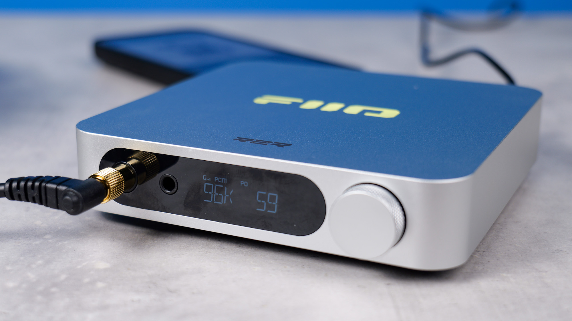 The FiiO K11 R2R on a stone surface with a headphone jack plugged in