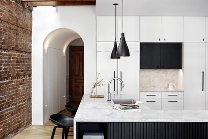 modern white kitchen with a brick wall and arched door