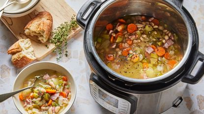 Stew inside an Instant Pot multi-cooker; beside it, a bowl of stew and a baguette on a chopping board.