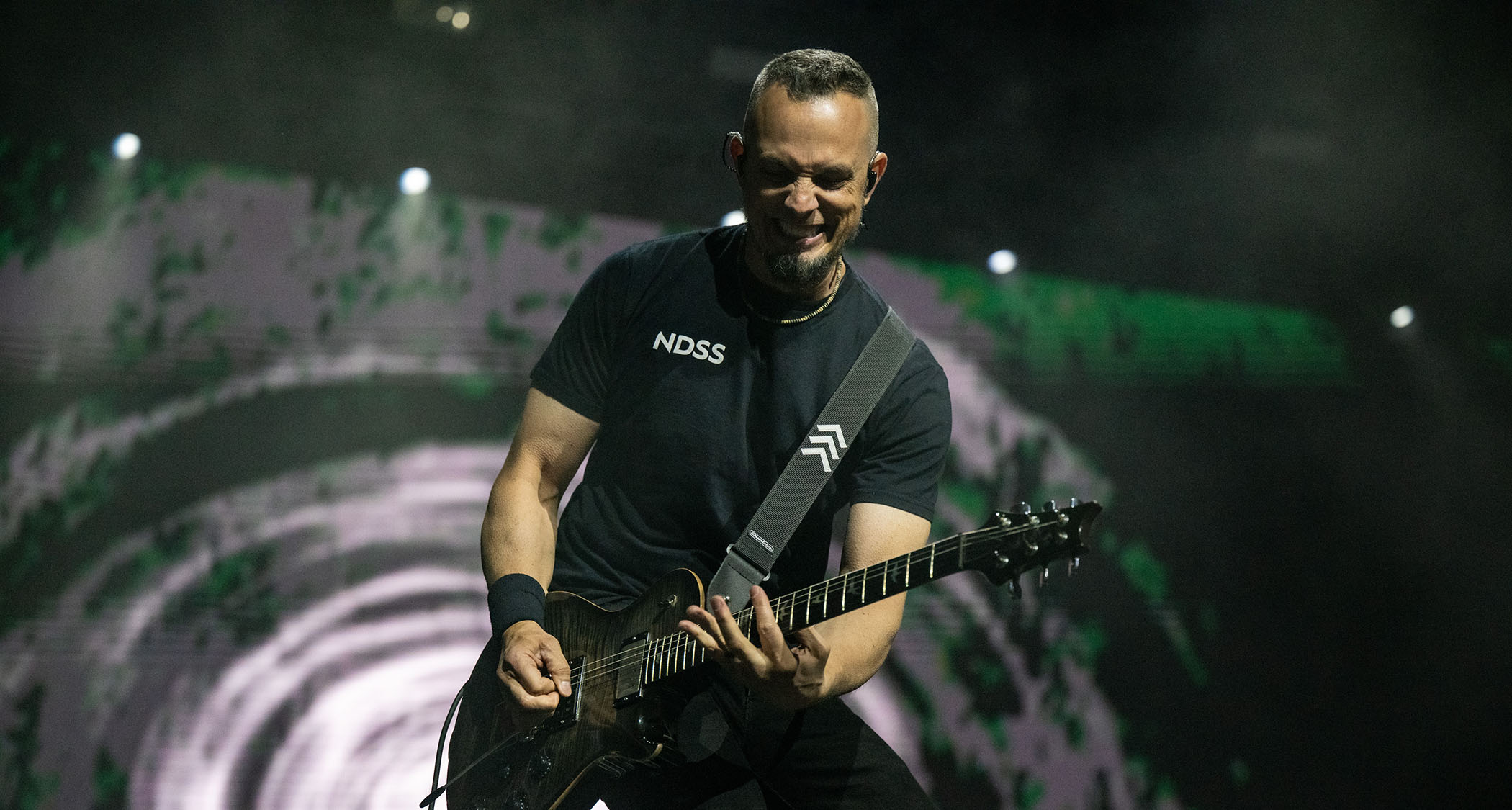 Mark Tremonti grimaces (or smiles?) as he plays a solo during a 2025 live show with his PRS signature guitar.