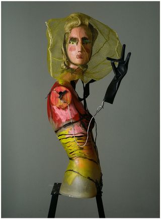 The Coquette, comprising a painted mannequin, netting from a package of firewood, a plastic cleaning glove, and a wig moulded with acrylic paint