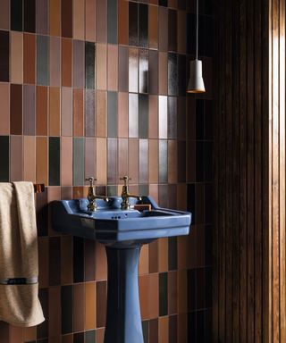 Tiled bathroom with multiple tones of brown collaged and blue enamel sink