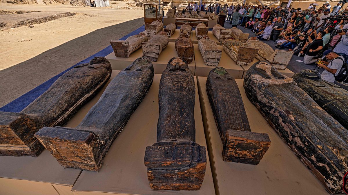 Sarcophaguses found in a cache dating to the Egyptian Late Period (around the fifth century BC). In the photo we can make out about 30 sarcophaguses laid out in four rows. They are underneath a massive tend are surround by a huge crowd of people taking photos.