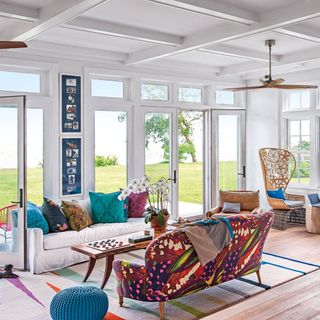 a conservatory with lots of windows, colourful furniture and striped rug