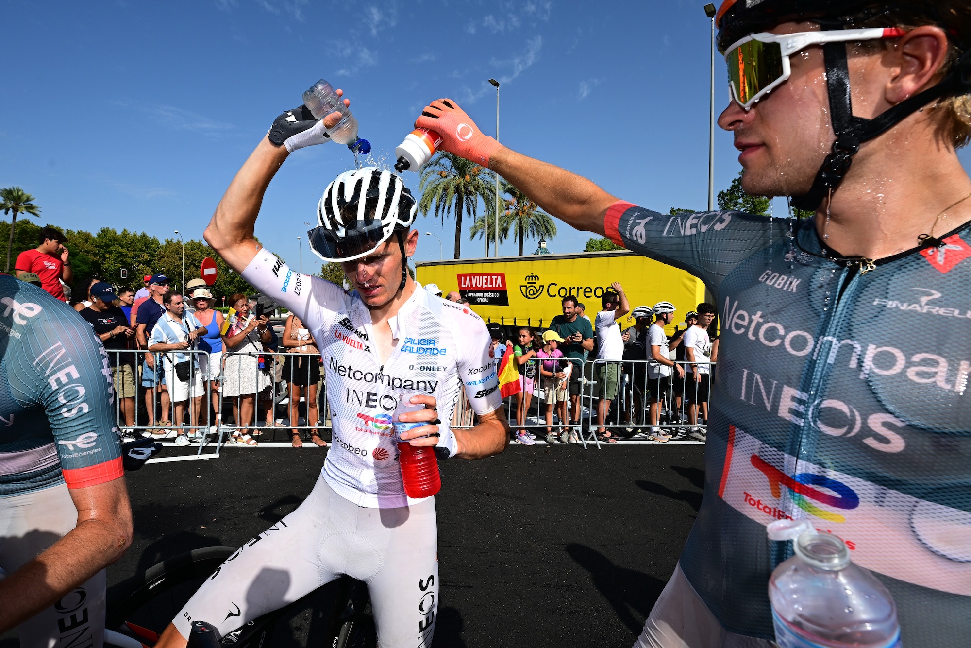 Oscar Onley, in the White Best Young Rider Jersey, cools down with lots of water with the help of Netcompany Ineos teammate Embret Svestad-Bardseng after the stage 15 finish